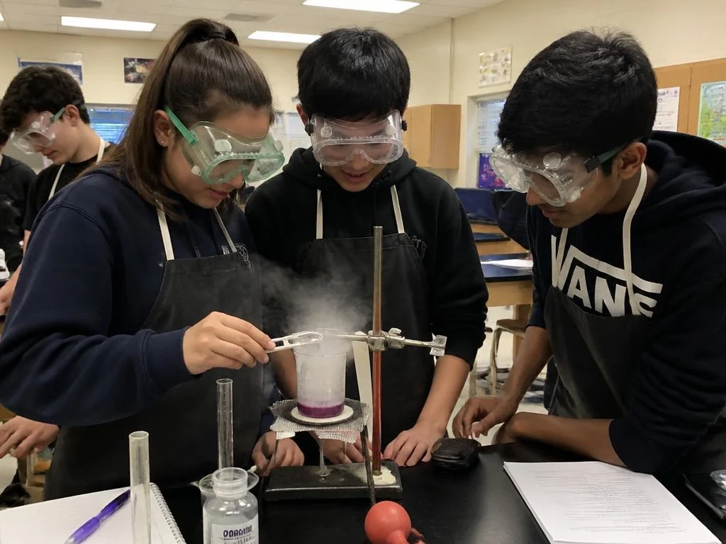 Students running a chemistry experiment in safety goggles